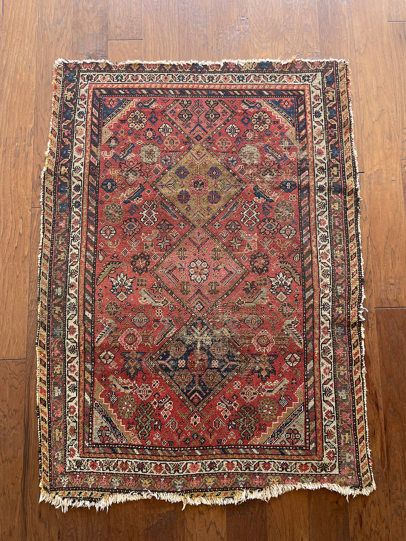 a vintage malayer rug with a raspberry pink field, lilac border and green and blue details