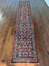 am antique heriz runner with a near black field and a pink and blue floral pattern