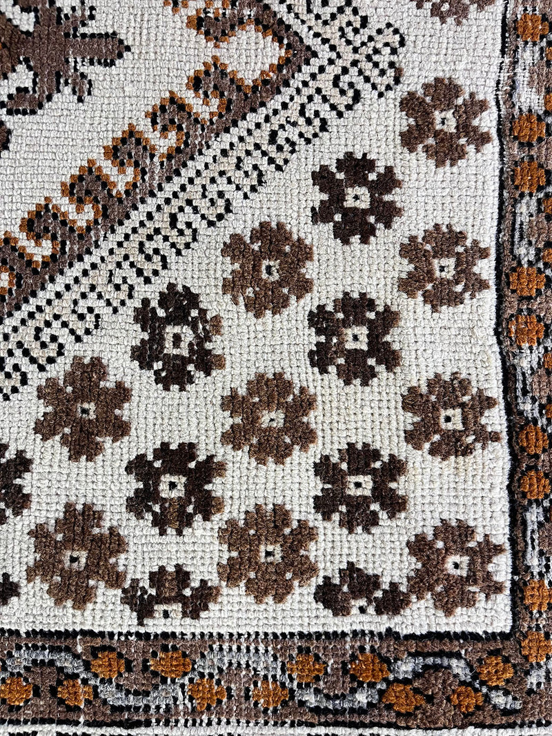 a vintage moroccan rug with a bright cream field and brown, orange and taupe accents