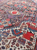 an antique qashqai rug with dark aubergine accents with cream, red and royal blue