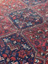 a vintage shiraz rug with a dark red field and dark blue medallions