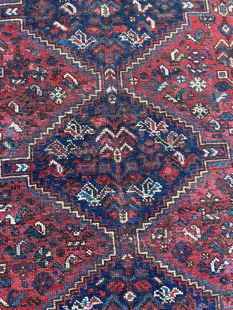 a vintage shiraz rug with a dark red field and dark blue medallions