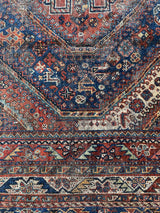 an antique qashqai rug with a beautiful navy blue field and a brick red border