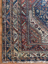 an antique qashqai rug with a beautiful navy blue field and a brick red border