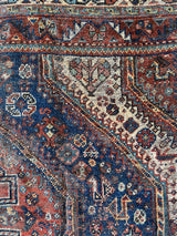 an antique qashqai rug with a beautiful navy blue field and a brick red border