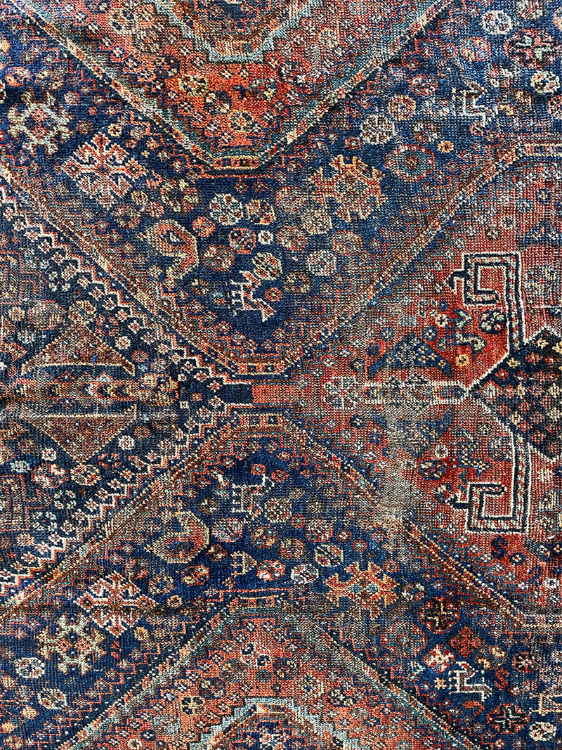 an antique qashqai rug with a beautiful navy blue field and a brick red border