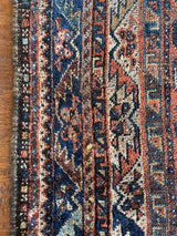 an antique qashqai rug with a beautiful navy blue field and a brick red border