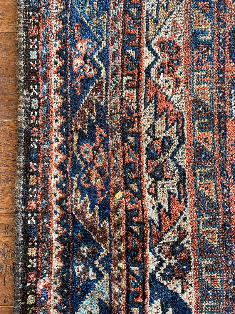 an antique qashqai rug with a beautiful navy blue field and a brick red border