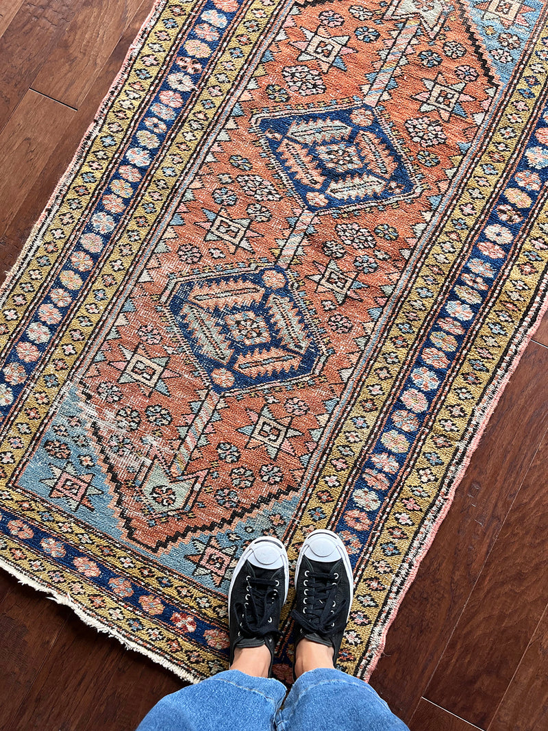 an antique heriz rug with a coral field and pretty pink, blue and lime green details