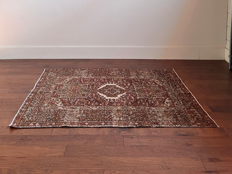 an antique heriz karajah rug with an earthy palette and warm red hues