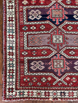 an antique caucasian rug with a red field and medallions in lilac and dark purple