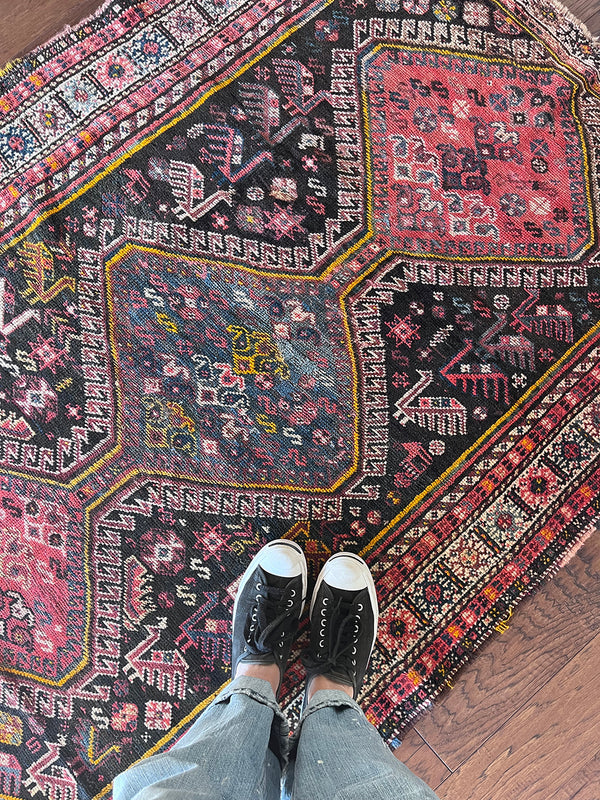 a vintage qashqai rug with a dark blue field and hot pink and yellow accents