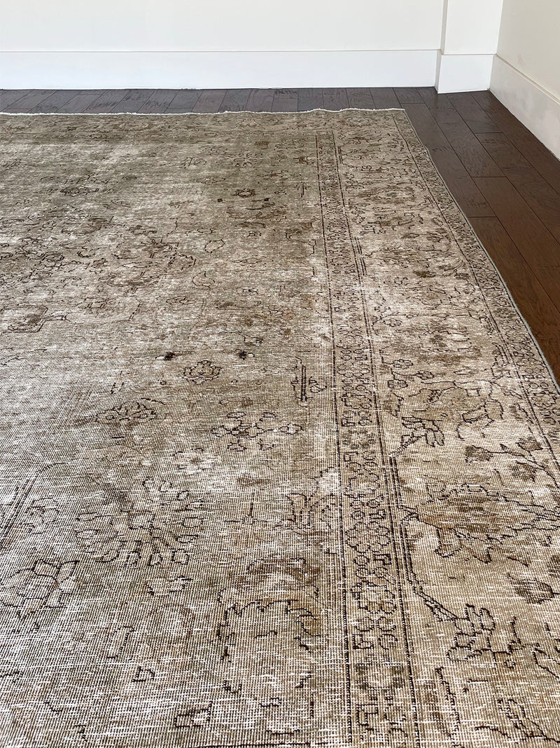 a vintage tabriz rug with a faded light sage green palette and a subtle floral pattern in brown and taupe