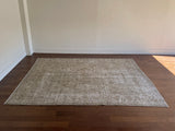 a vintage tabriz rug with a faded light sage green palette and a subtle floral pattern in brown and taupe