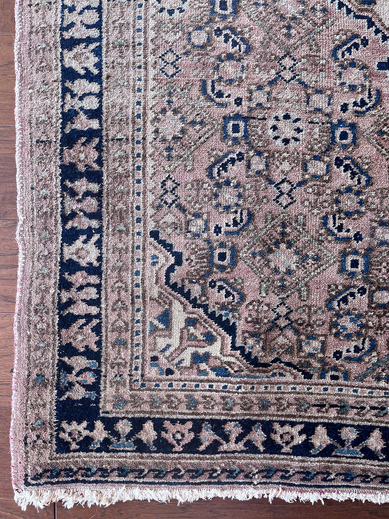 a mini antique malayer rug with a pink field and dark blue details 
