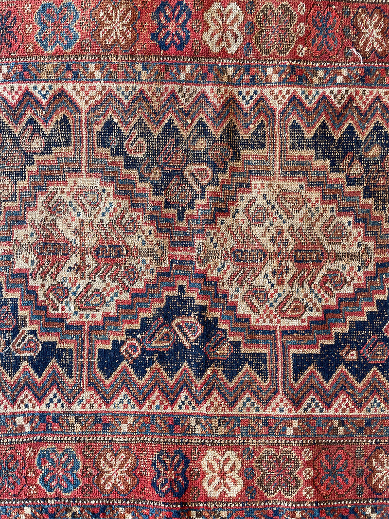 a mini antique afshar rug with a dark blue field, pretty checkerboard border detail and warm red details