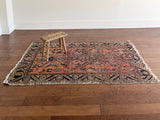 an antique bakshaish rug with a salmon pink field and green and teal floral pattern