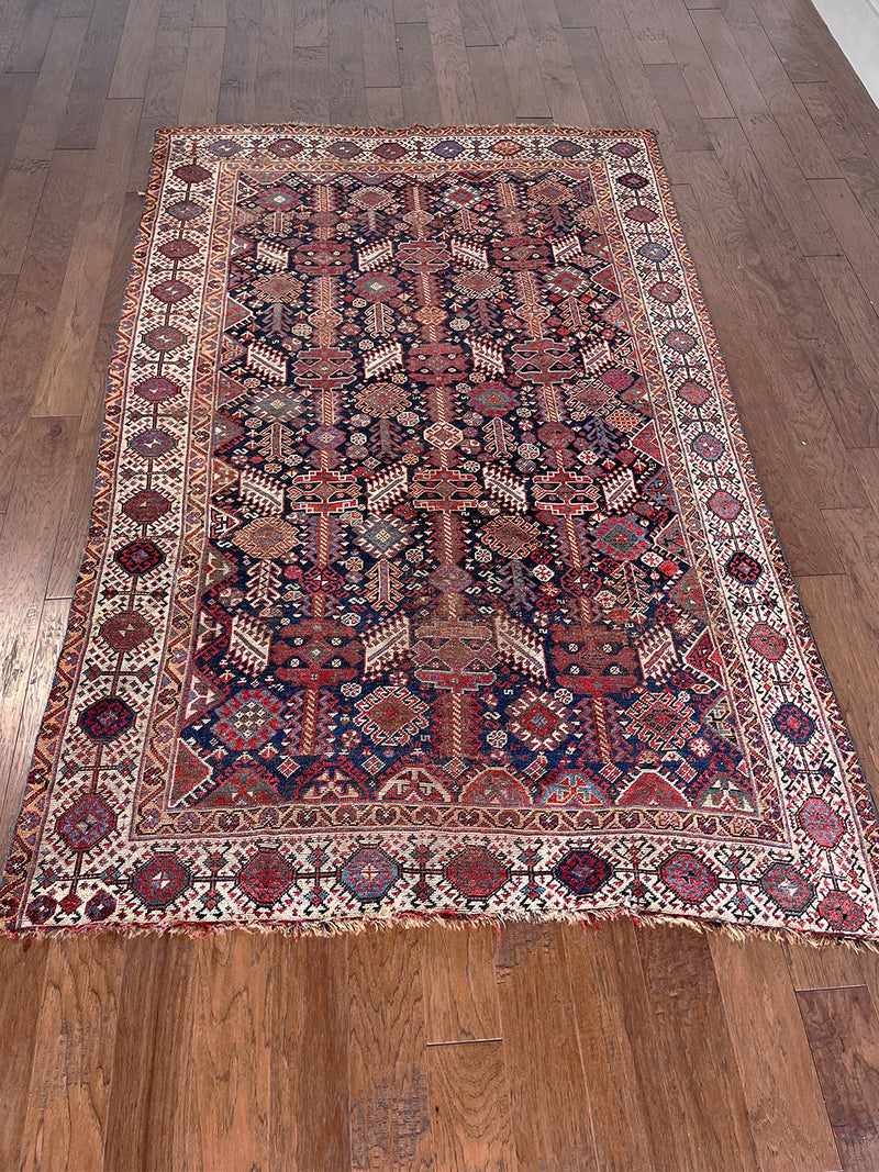 an antique qashqai rug with a midnight blue field and white, yellow and red accents 