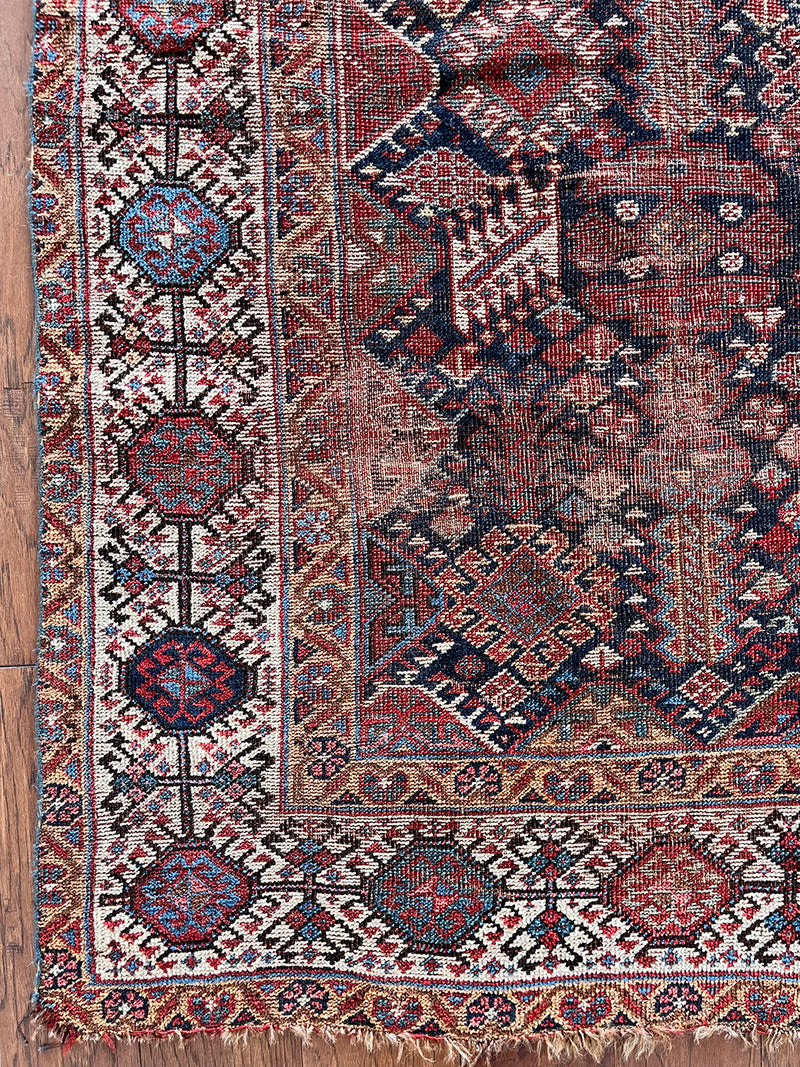 an antique qashqai rug with a midnight blue field and white, yellow and red accents 