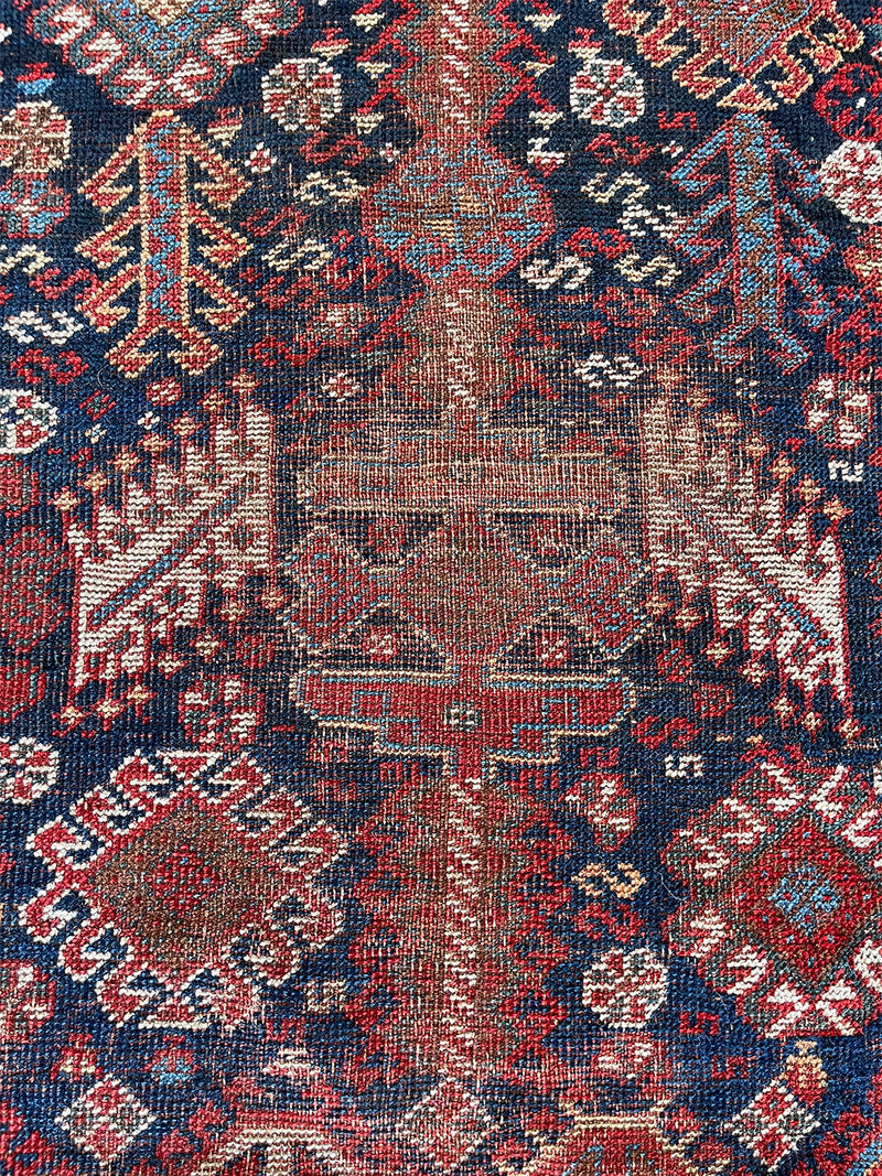 an antique qashqai rug with a midnight blue field and white, yellow and red accents 