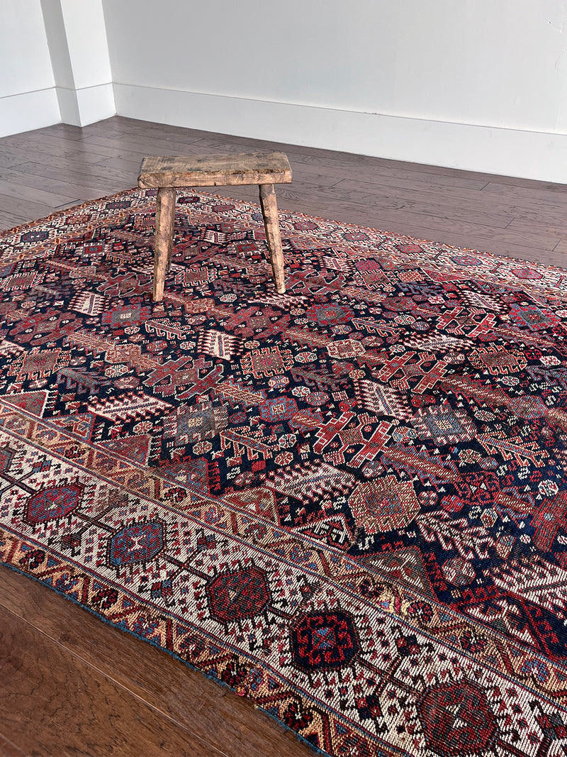 an antique qashqai rug with a midnight blue field and white, yellow and red accents 