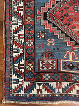 an antique caucasian rug with a blue field with faded red medallions