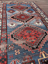 an antique caucasian rug with a blue field with faded red medallions