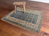 an antique caucasian kuba rug with a navy blue field and brown accents