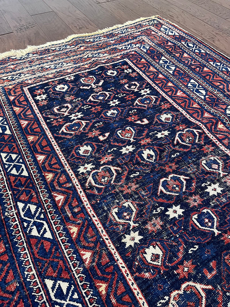 an antique caucasian shirwan rug with a navy blue field and a red border