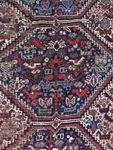 an antique qashqai rug with a dark field and blue, red and ivory accents