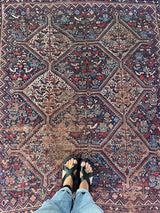 an antique qashqai rug with a dark field and blue, red and ivory accents