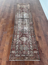 an antique heriz karajah runner with a deep wine red and brown palette and light pink and yellow accents