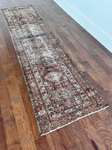 an antique heriz karajah runner with a deep wine red and brown palette and light pink and yellow accents