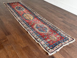 an antique heriz runner with a red field and blue, green and mustard medallions