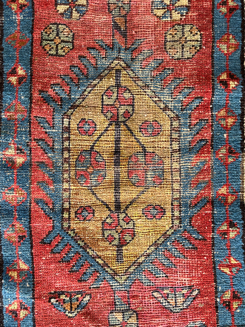 an antique heriz runner with a red field and blue, green and mustard medallions