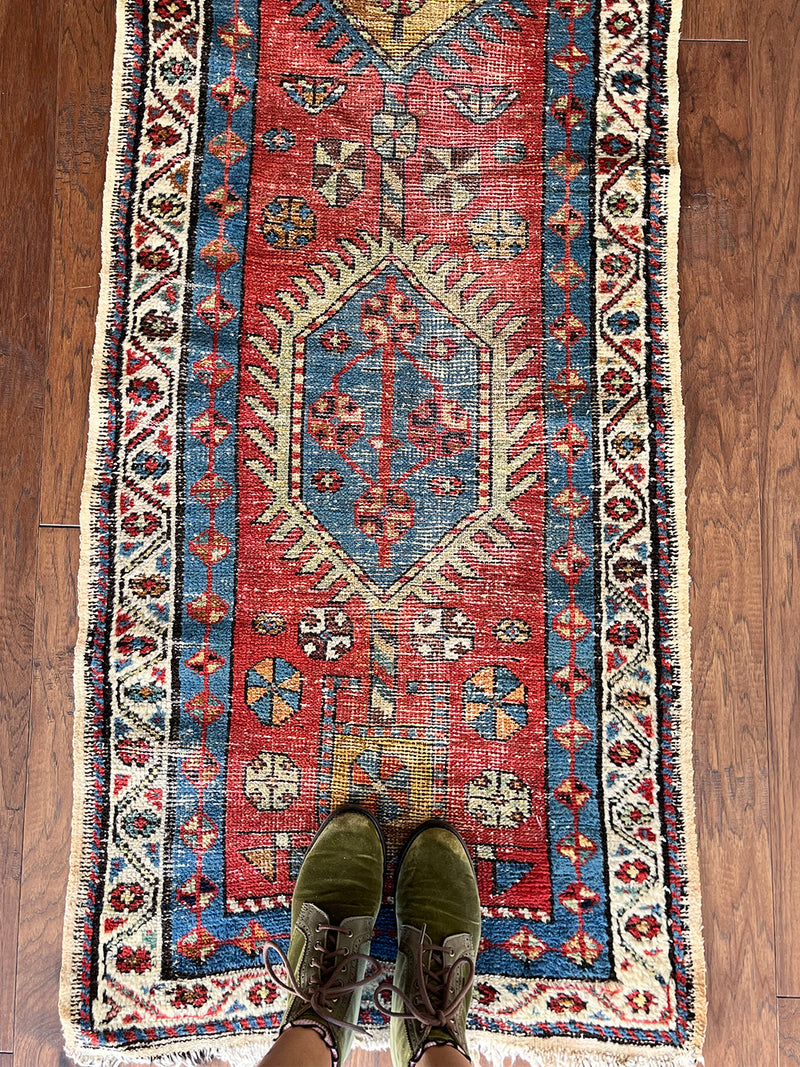 an antique heriz runner with a red field and blue, green and mustard medallions