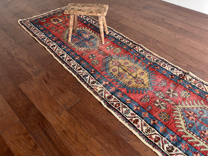 an antique heriz runner with a red field and blue, green and mustard medallions