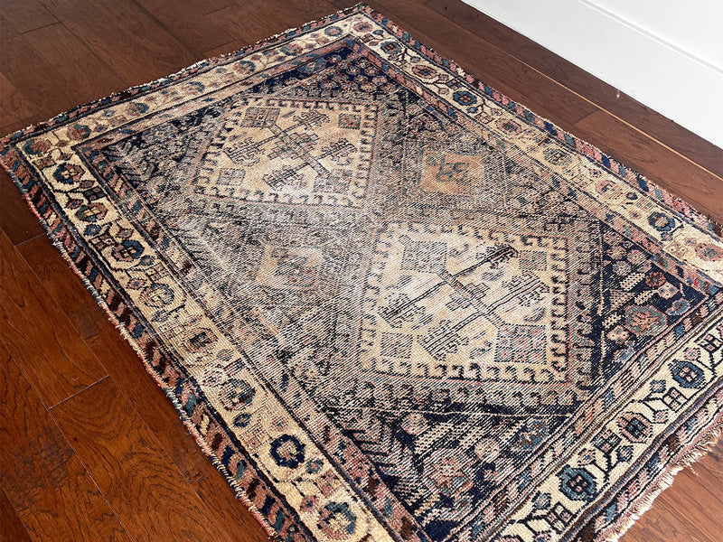 an antique afshar rug with a dark blue and ivory palette and pretty coral accents