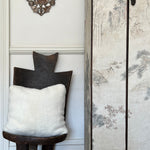 a white shearling pillow backed in plush velvet, with an exposed brass zipper