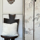 a white shearling pillow backed in plush velvet, with an exposed brass zipper