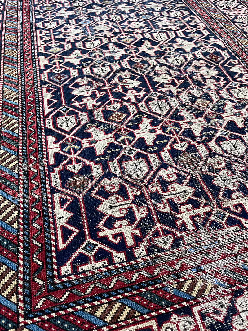 an antique caucasian shirwan rug with a dark blue field and a geometric pattern in cream