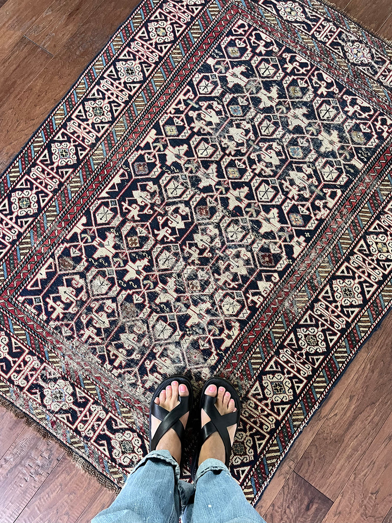 an antique caucasian shirwan rug with a dark blue field and a geometric pattern in cream