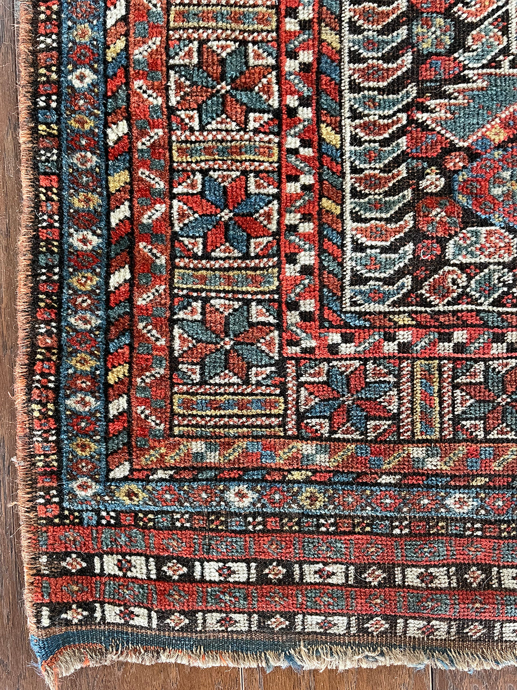 an antique qashqai rug with a dark blue field and intricate colourful details