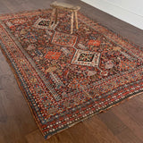an antique qashqai rug with a dark blue field and intricate colourful details