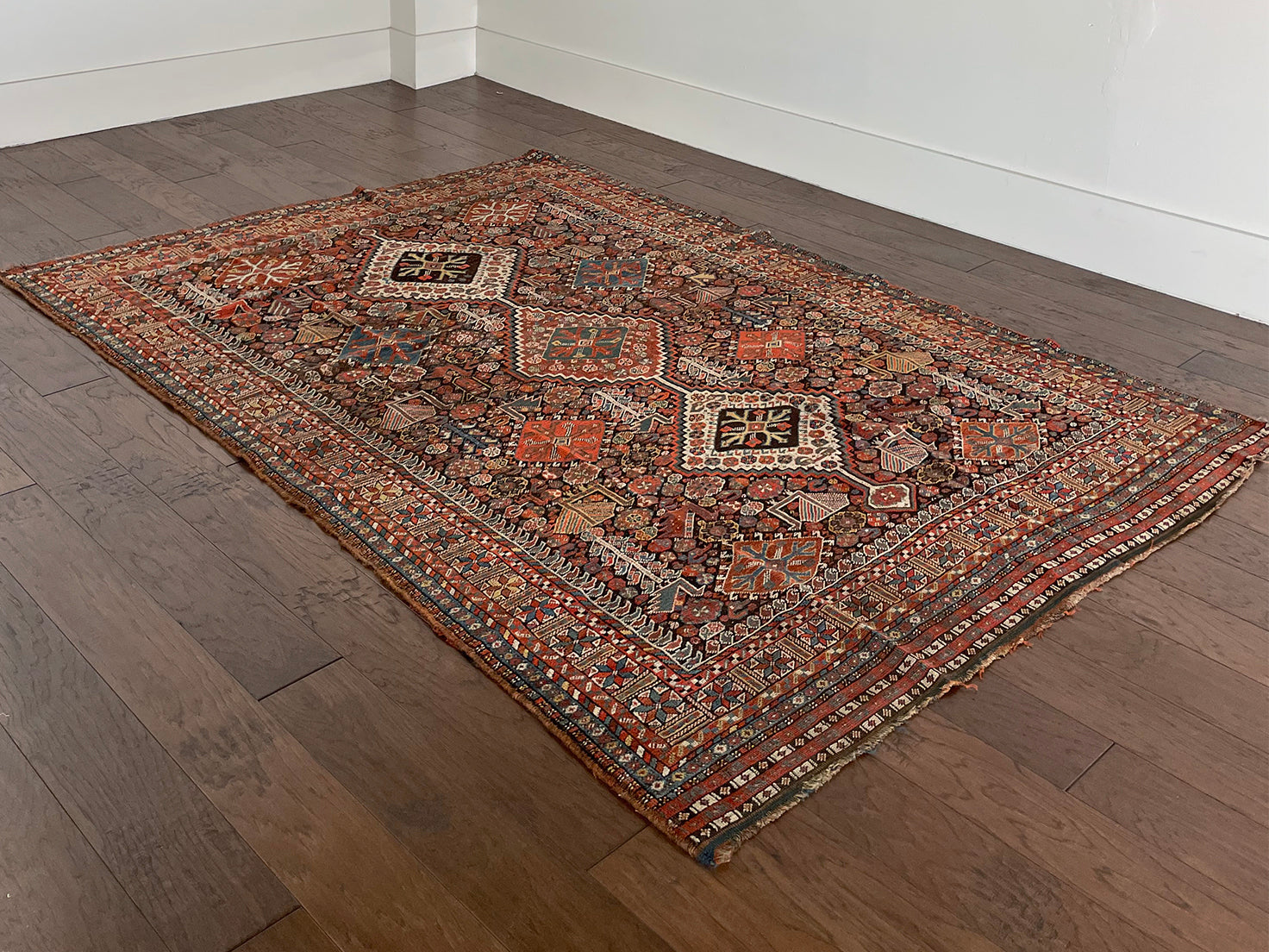 an antique qashqai rug with a dark blue field and intricate colourful details