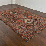 an antique qashqai rug with a dark blue field and intricate colourful details