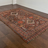 an antique qashqai rug with a dark blue field and intricate colourful details
