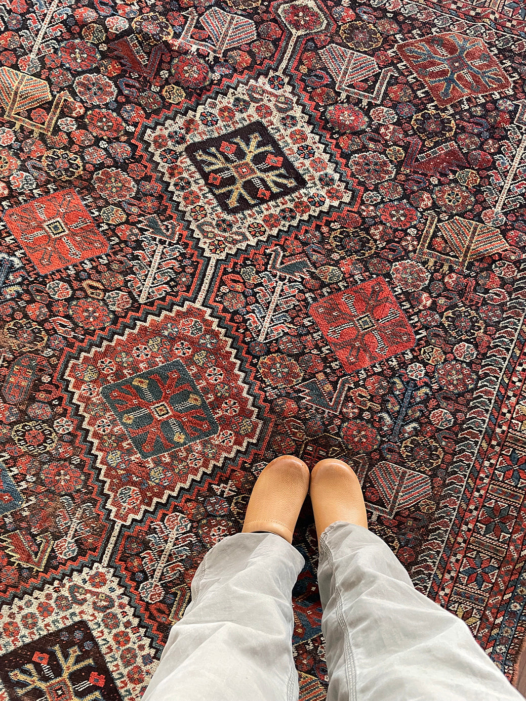 an antique qashqai rug with a dark blue field and intricate colourful details
