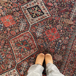 an antique qashqai rug with a dark blue field and intricate colourful details