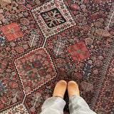 an antique qashqai rug with a dark blue field and intricate colourful details